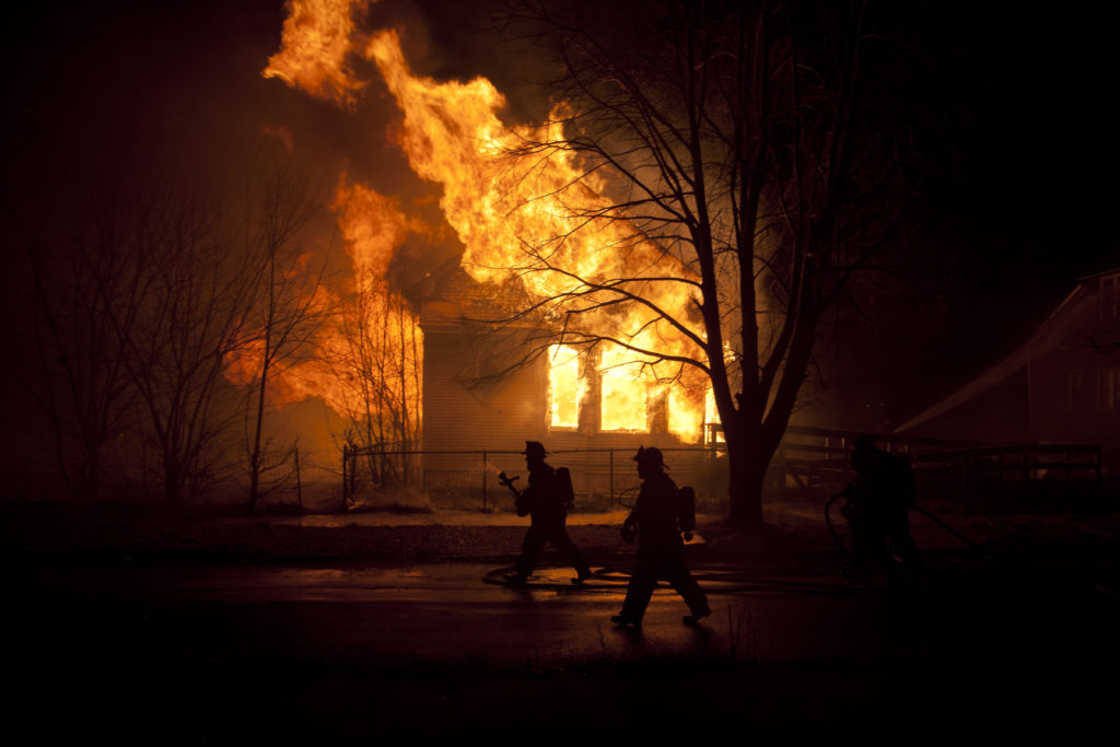 2012-03-06 23:09:35 Canon EOS 5D Mark II f/6.3 1/125sec ISO-200 28mm Detroit, United States - March 12th, 2012: Firefighters walk past a vacant house burning on Hidelberg Street in Detroit, Michigan. Water supply issues prevented firefighters from attacking the blaze, which was brought under control in 30 minutes. The house at 3142 Hidelberg Street was completely destroyed. John Grover
